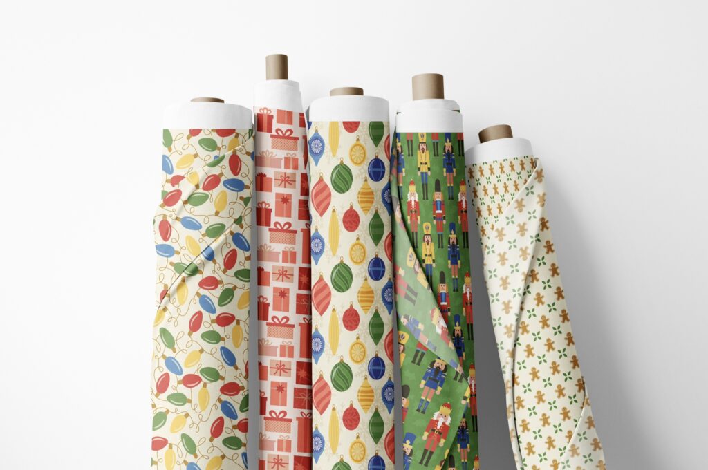 Five fabric rolls leaning up against a wall. Christmas fabric patterns.