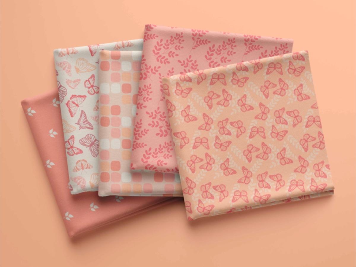 Five folded fabric swatches featuring the Pantone Color of the Year "Peach Fuzz"