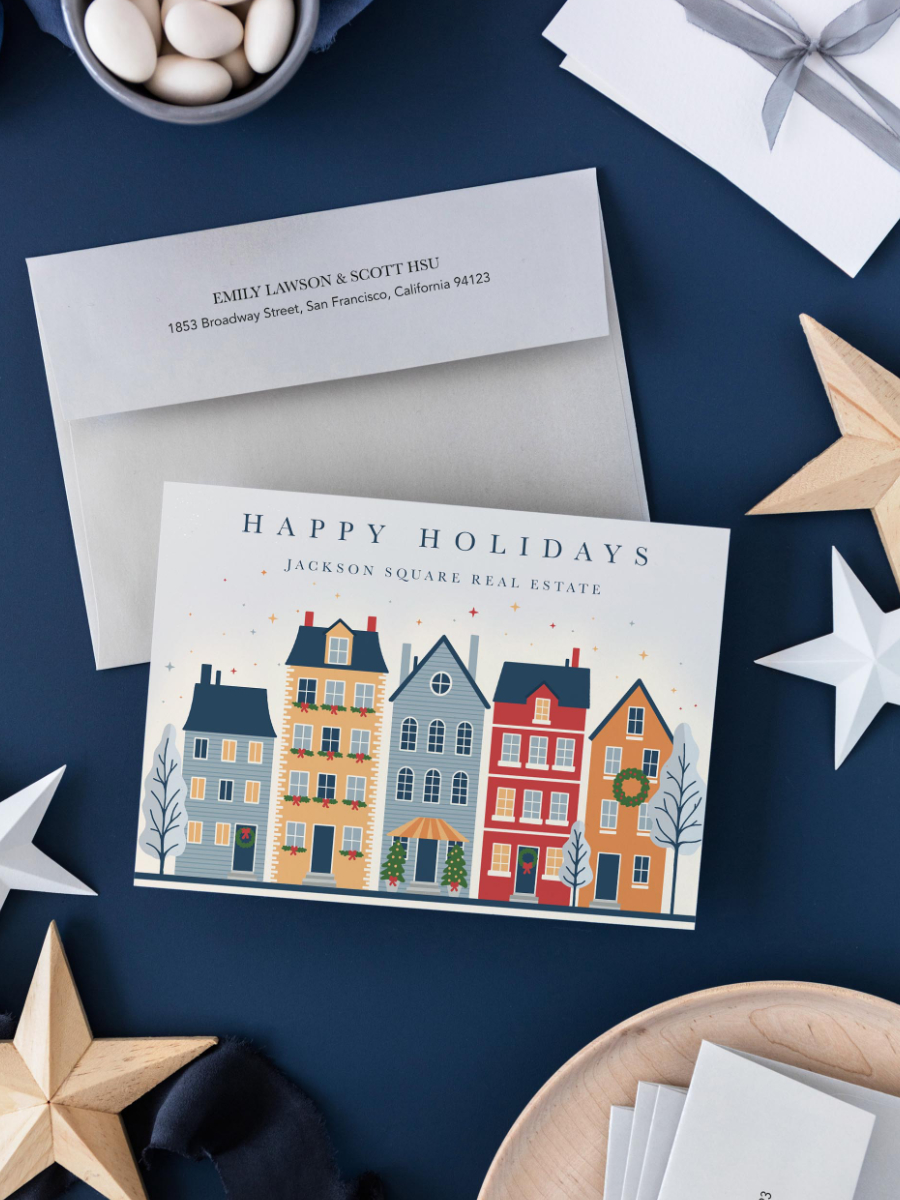 Corporate Christmas card featuring a snowy European street scene with decorated townhouses, twinkling lights and festive wreaths.